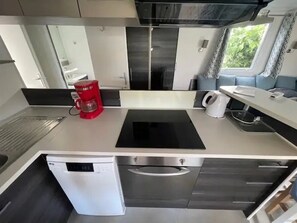 Une cuisine compacte équipée d’une machine à café, d’une bouilloire et d’un lave-vaisselle.
