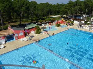 Ein Schwimmbecken mit mehreren Bahnen, Liegestühlen und Sonnenschirmen.