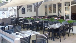 An outdoor dining area with tables and chairs, a covered seating area, and a staircase leading to an upper level. - Camping 4 étoiles - Parc aquatique - ccbfgac (Les Mathes)