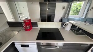 A compact kitchen with a coffee maker, a kettle, and a dishwasher. - Camping 4 étoiles - Parc aquatique - ccbfgac (Les Mathes)