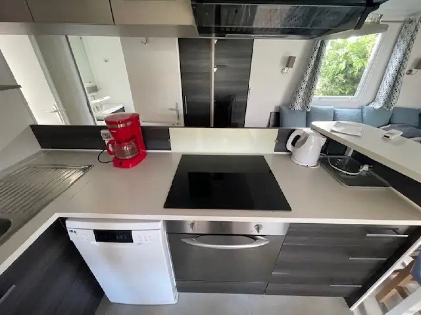 Una cocina compacta equipada con cafetera, hervidor y lavavajillas.