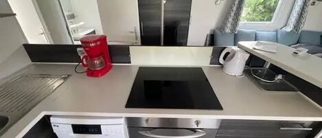 Una cocina compacta equipada con cafetera, hervidor y lavavajillas.