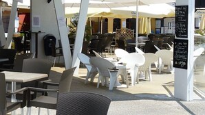 An outdoor cafe with tables and chairs, umbrellas, and a chalkboard menu. - Camping 4 étoiles - Parc aquatique - ccbfgai (Les Mathes)