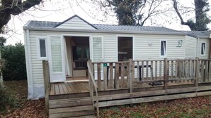 Une maison mobile de plain-pied dotée d’une terrasse en bois et d’une porte d’entrée.