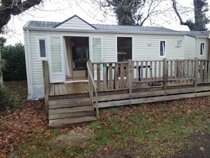 A single-story mobile home with a wooden deck and a front door.