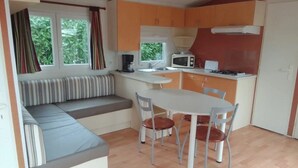 Une cuisine compacte comprenant une table et des chaises, un four à micro-ondes et un banc intégré avec des coussins.