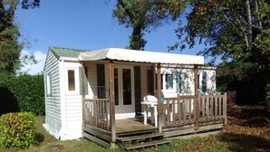 A small, single-story wooden structure with a porch and a white chair. - Camping 3 étoiles - ccbfgdd (Neuvic)