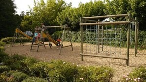 A playground with a slide, climbing structures, and a fenced area. - Camping 3 étoiles - ccbfgdd (Neuvic)