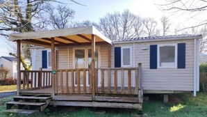 Ein eingeschossiges Mobilheim mit Veranda, einer kleinen Veranda und einem überdachten Eingangsbereich.