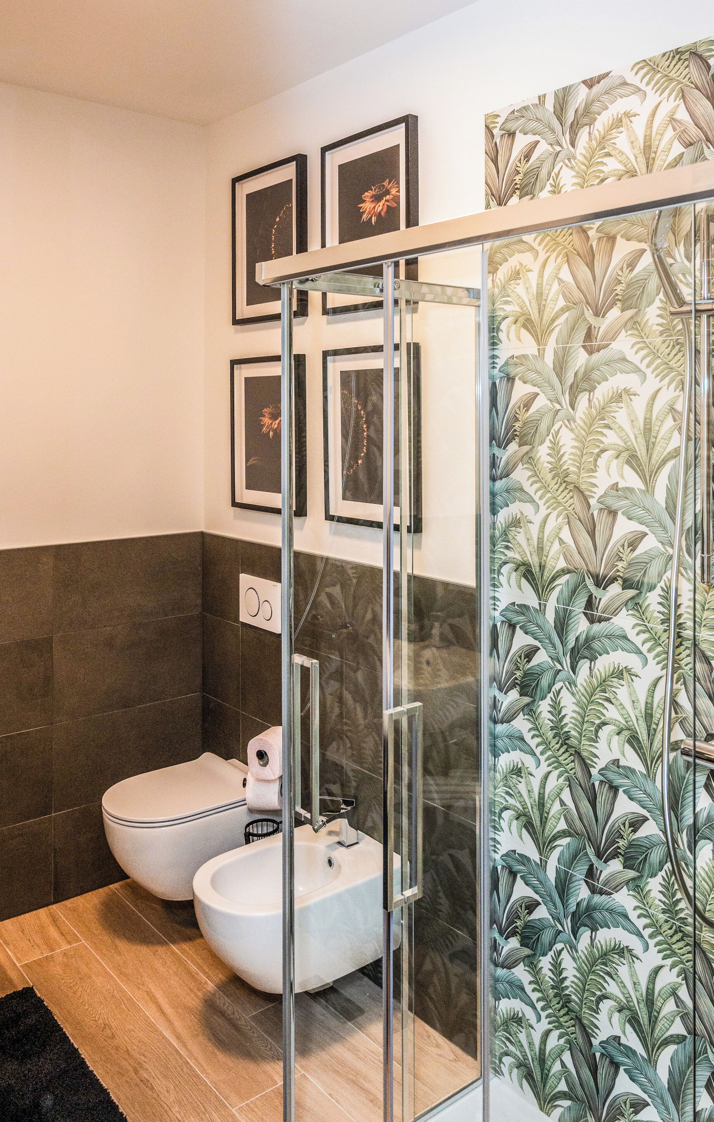 A modern bathroom with a glass shower enclosure, a toilet, and a bidet.