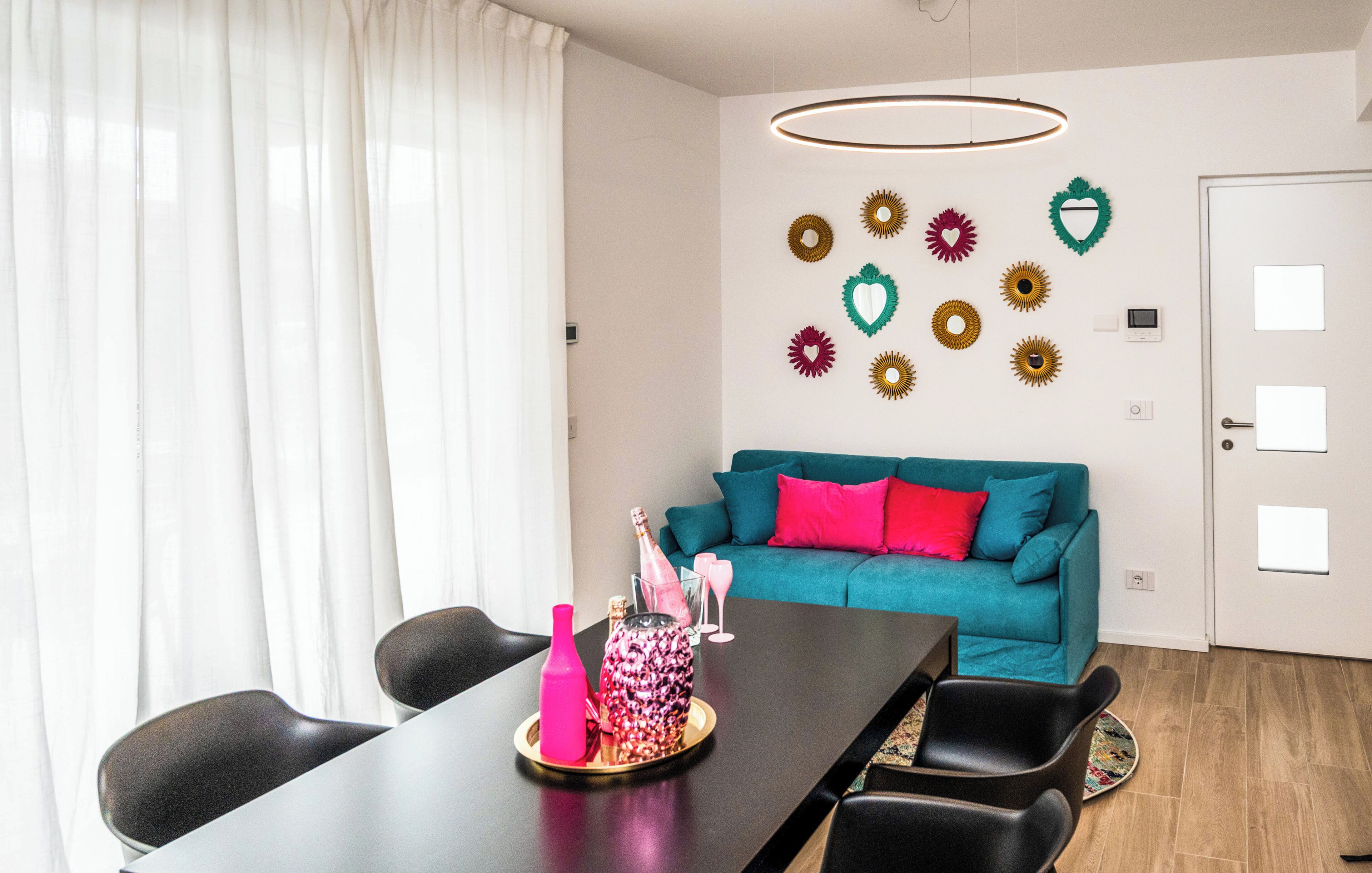 Un salon moderne avec une table à manger, un canapé de couleur turquoise et des œuvres d’art décoratives au mur.