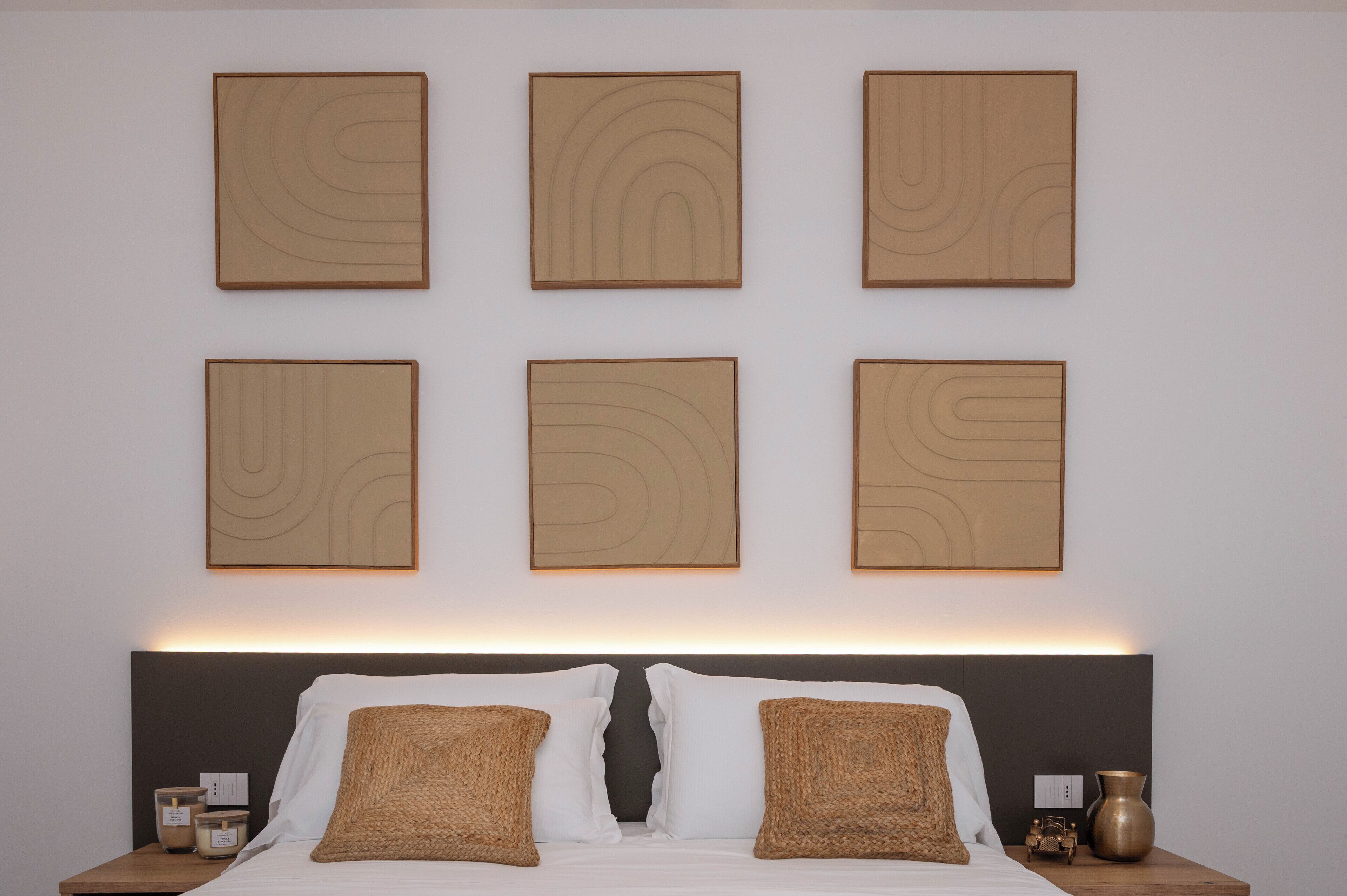 A neatly arranged bedroom with a bed, two bedside tables, and six wall-mounted artworks.