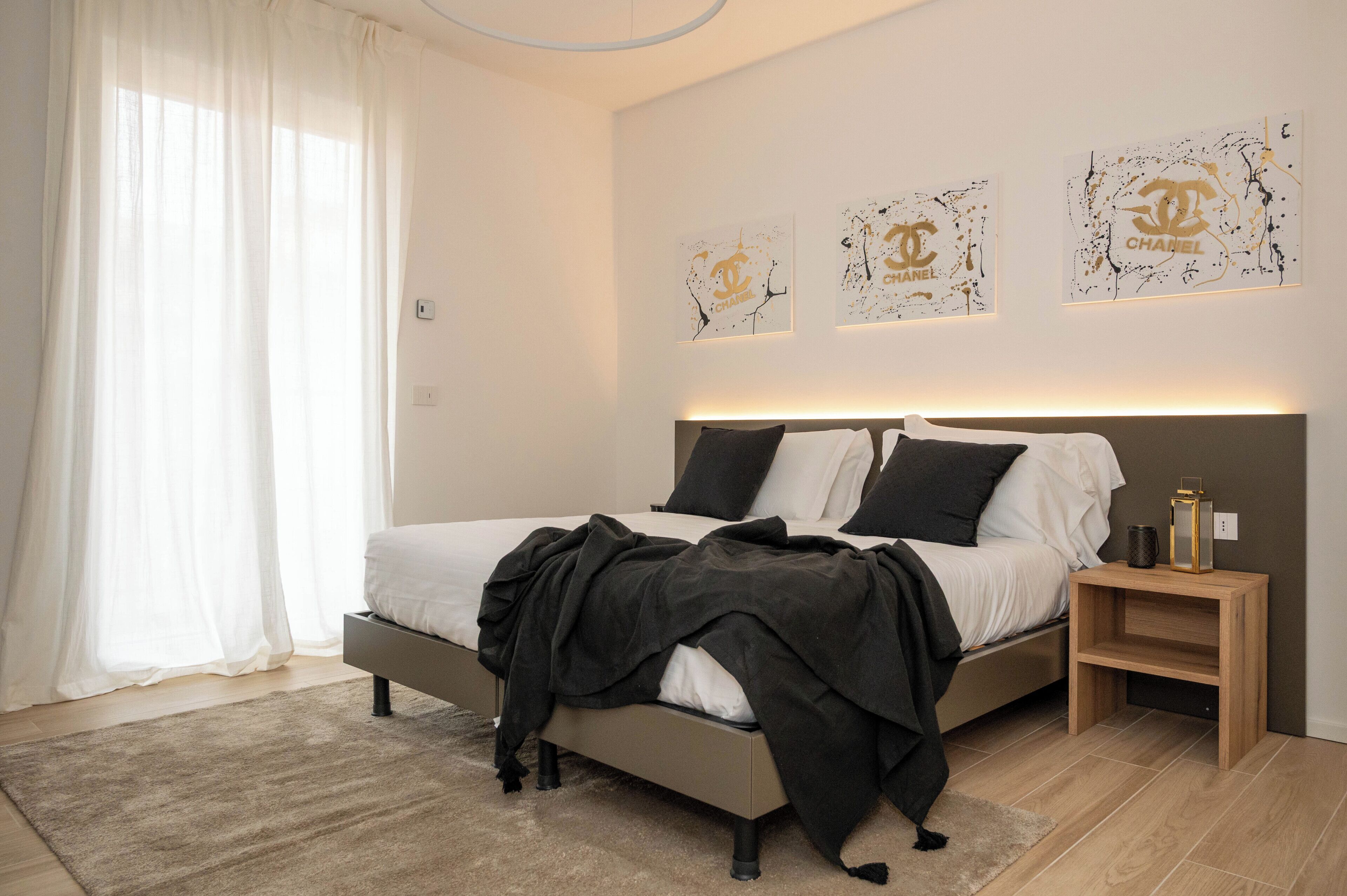 A bedroom with a bed, a bedside table, and wall art.