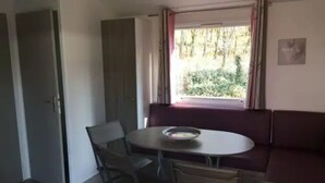 Ein Zimmer mit Esstisch, Stühlen, einer Couch, einem Fenster mit Vorhängen und einer Tür.