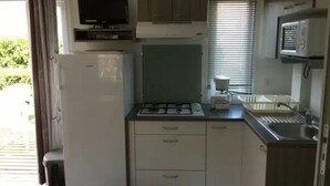 Eine kleine Küche mit Kühlschrank, Mikrowelle, Herd und Spüle.