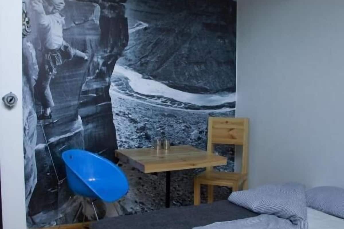 A bedroom with a bed, a desk, a chair, and a blue chair.