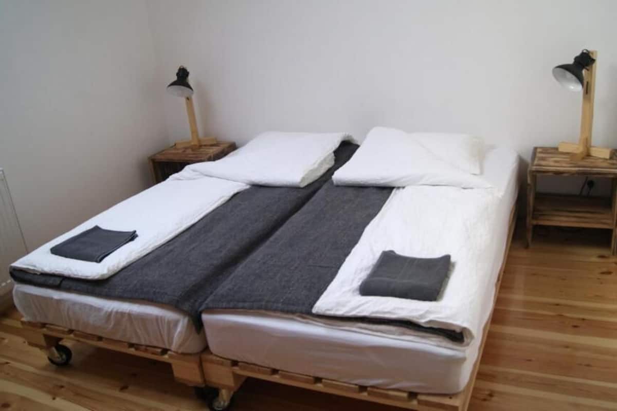 A double bed with a wooden frame, two bedside tables, and two floor lamps.