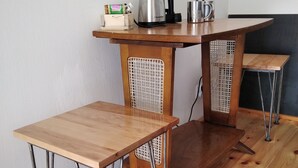 A wooden table with metal legs, a coffee maker, and a kettle on top.