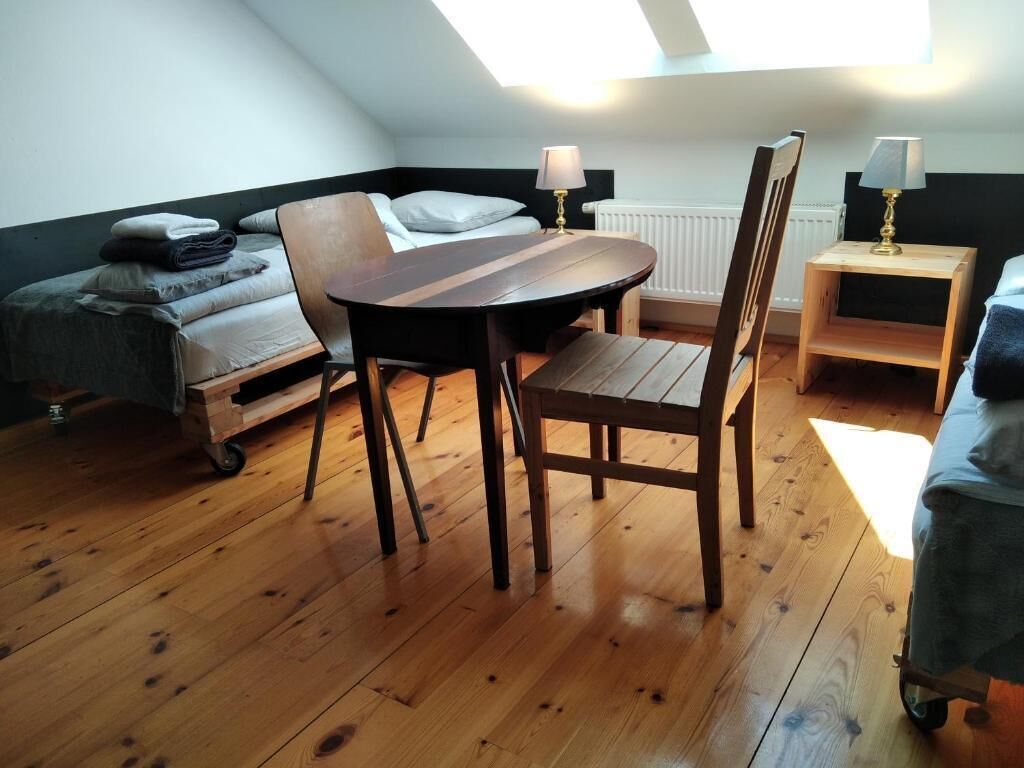 A loft-style room with a bed, a table, chairs, and a radiator.