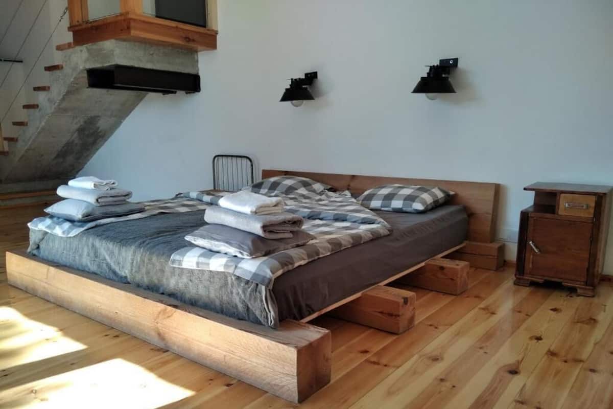 A bedroom with a wooden bed frame, a headboard, a nightstand, and a built-in bench.