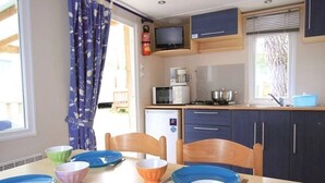 Eine kleine Küche mit Mikrowelle, Toaster und Herd, Holzstühle und ein Esstisch mit Tellern und Schüsseln.