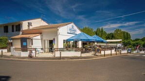 Ein Restaurant mit Außenbereich, einer blauen Markise und einem Schild mit der Aufschrift 'LES FILS DE LA BRIE'.