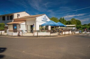 Ein Restaurant mit Außenbereich, einer blauen Markise und einem Schild mit der Aufschrift 'LES FILS DE LA BRIE'.