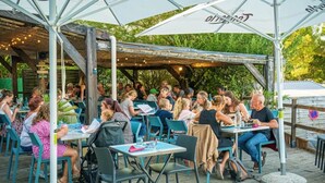 Ein Außenbereich zum Essen mit Tischen und Stühlen, ein überdachter Sitzbereich und eine Holzterrasse.