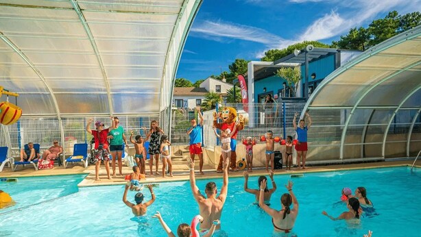 Ein Poolbereich mit überdachtem Teil, Liegestühlen und einer Maskottchenfigur.