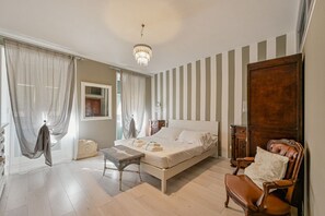 A bedroom with a bed, a chair, a table, curtains, a chandelier, and a wooden door. - A cozy and bright 81 sqm apartment, perfect for four guests, located on the first floor of a period building (no elevator).The property, which boasts a splendid view of the village, is situated in Riomaggiore—one of the famous Cinque Terre—just 5 m (Riomaggiore)