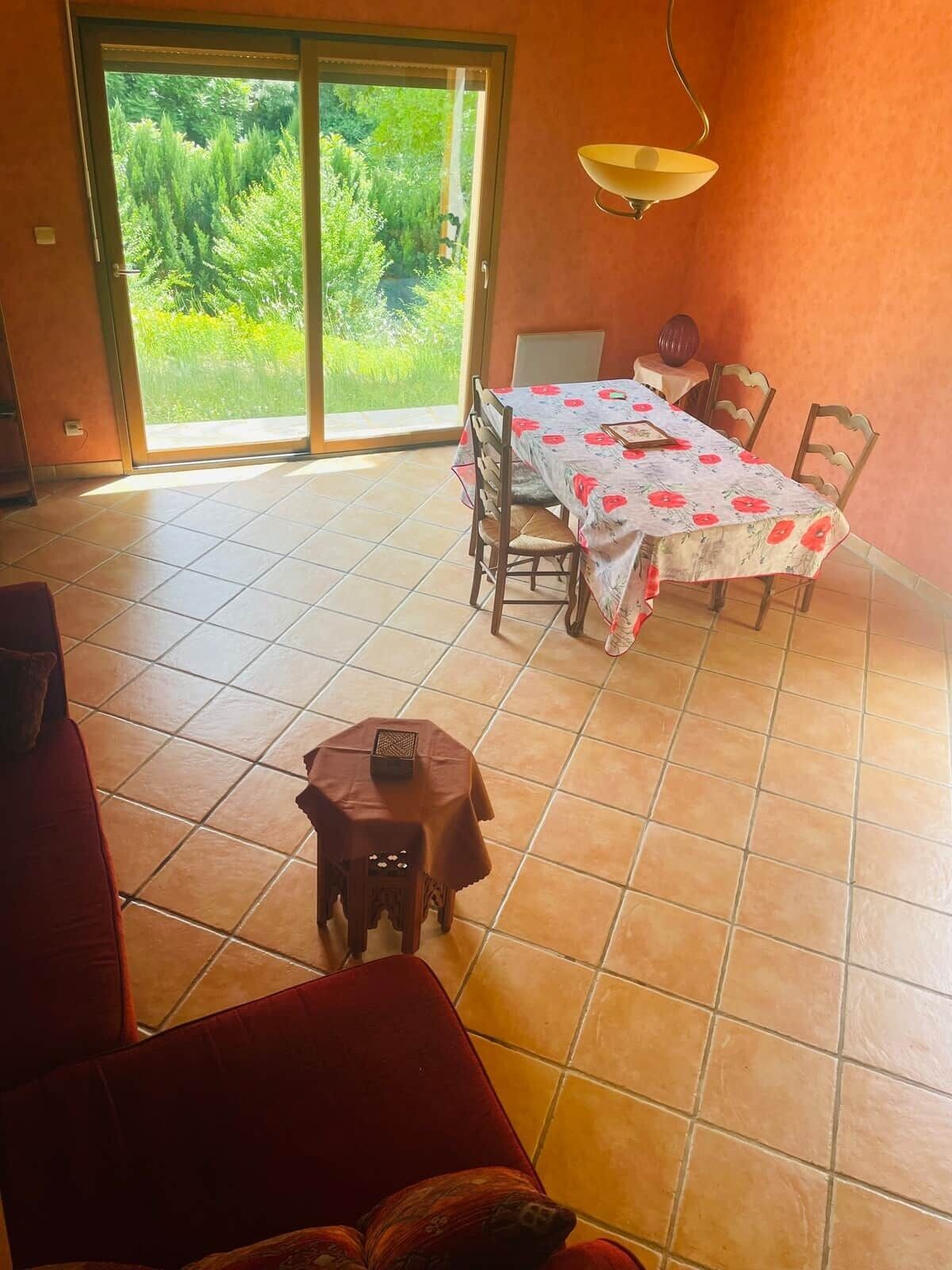 Un espace repas comprenant une table et des chaises, un petit tabouret et un canapé.