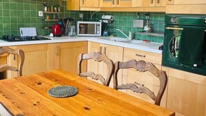 A kitchen with wooden cabinets, a microwave, a stove, and a dining table with chairs. - Vacation home for 6 in a quiet location (Saint-Cybranet)