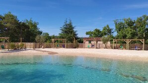 Uma piscina azul límpida com um deck de madeira, cercada por uma cerca de madeira e árvores.