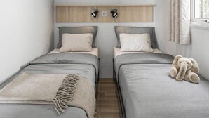 Quarto com duas camas, um armário em cima e uma janela com cortinas.
