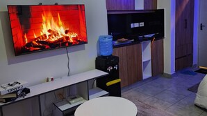 A living room with a flat-screen TV, a small table, and a water dispenser.