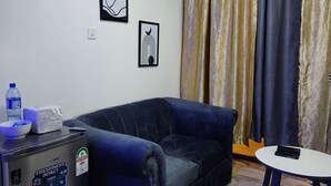 A compact living space with a sofa, a small table, and a refrigerator.