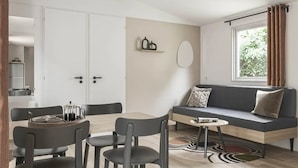 Uma sala de estar moderna com um sofá, cadeiras, uma mesa de centro e um espaço para refeições.