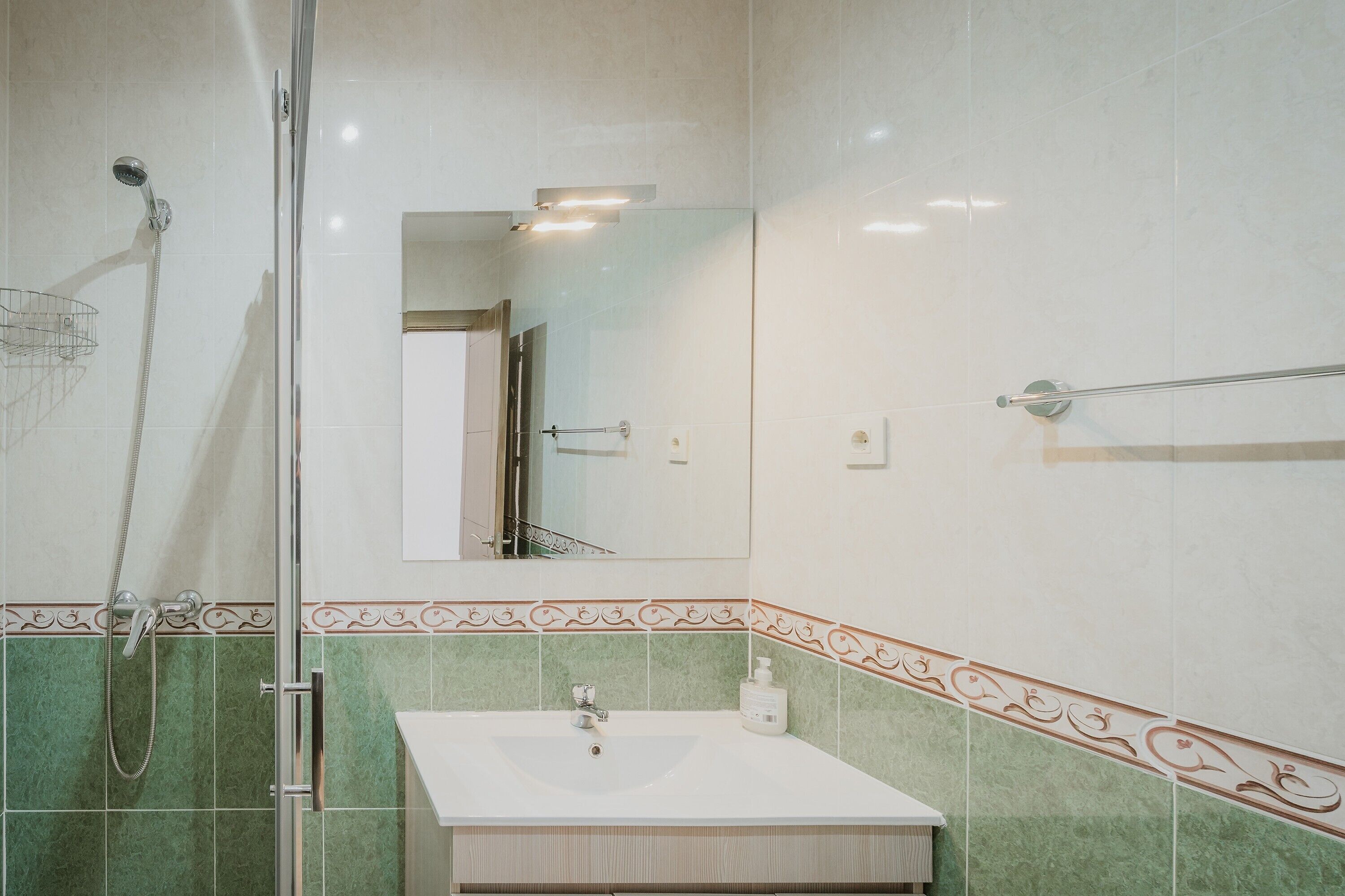 A bathroom with a shower, sink, and mirror.