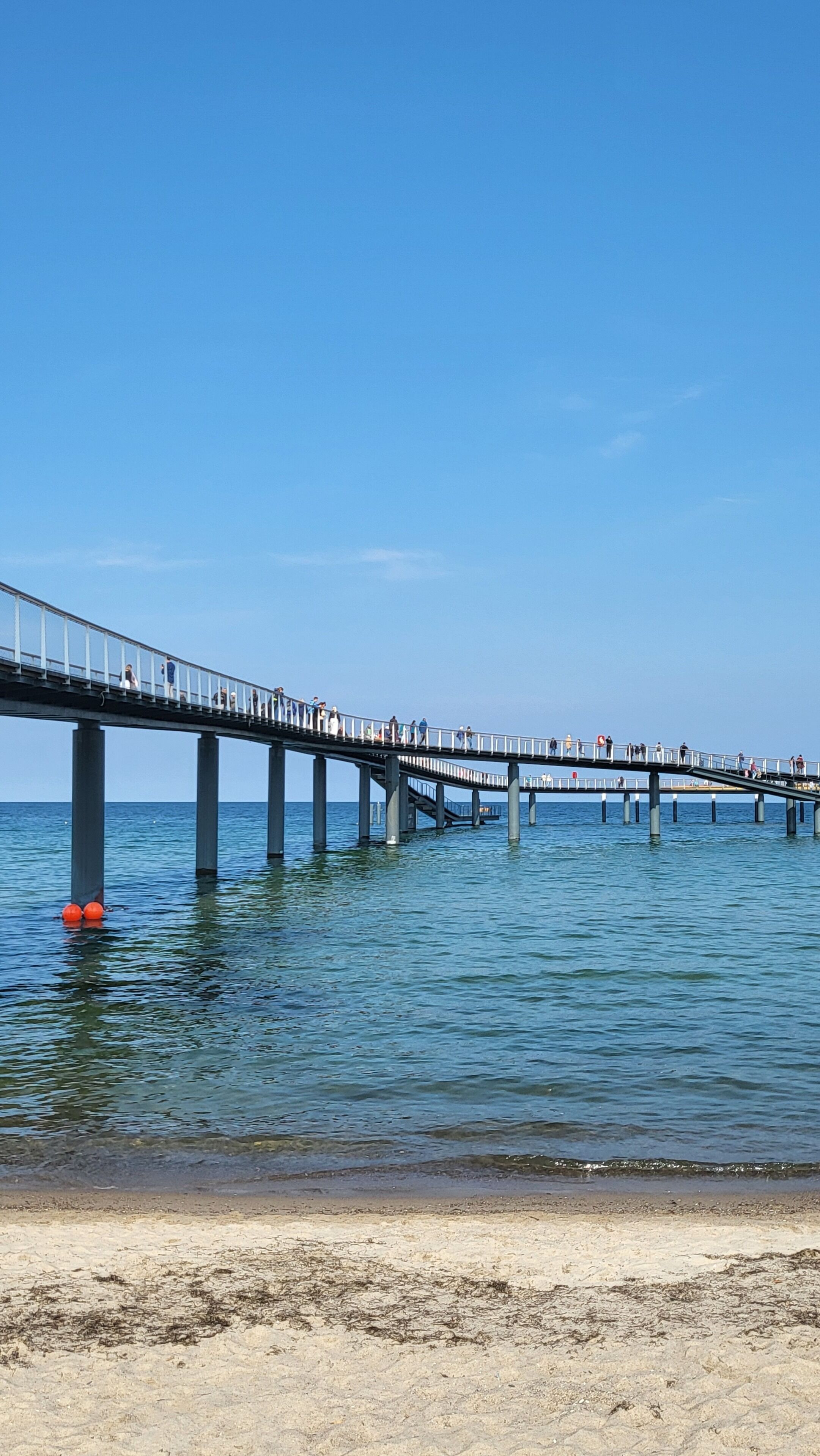 A pier extending into calm water with a clear sky above.