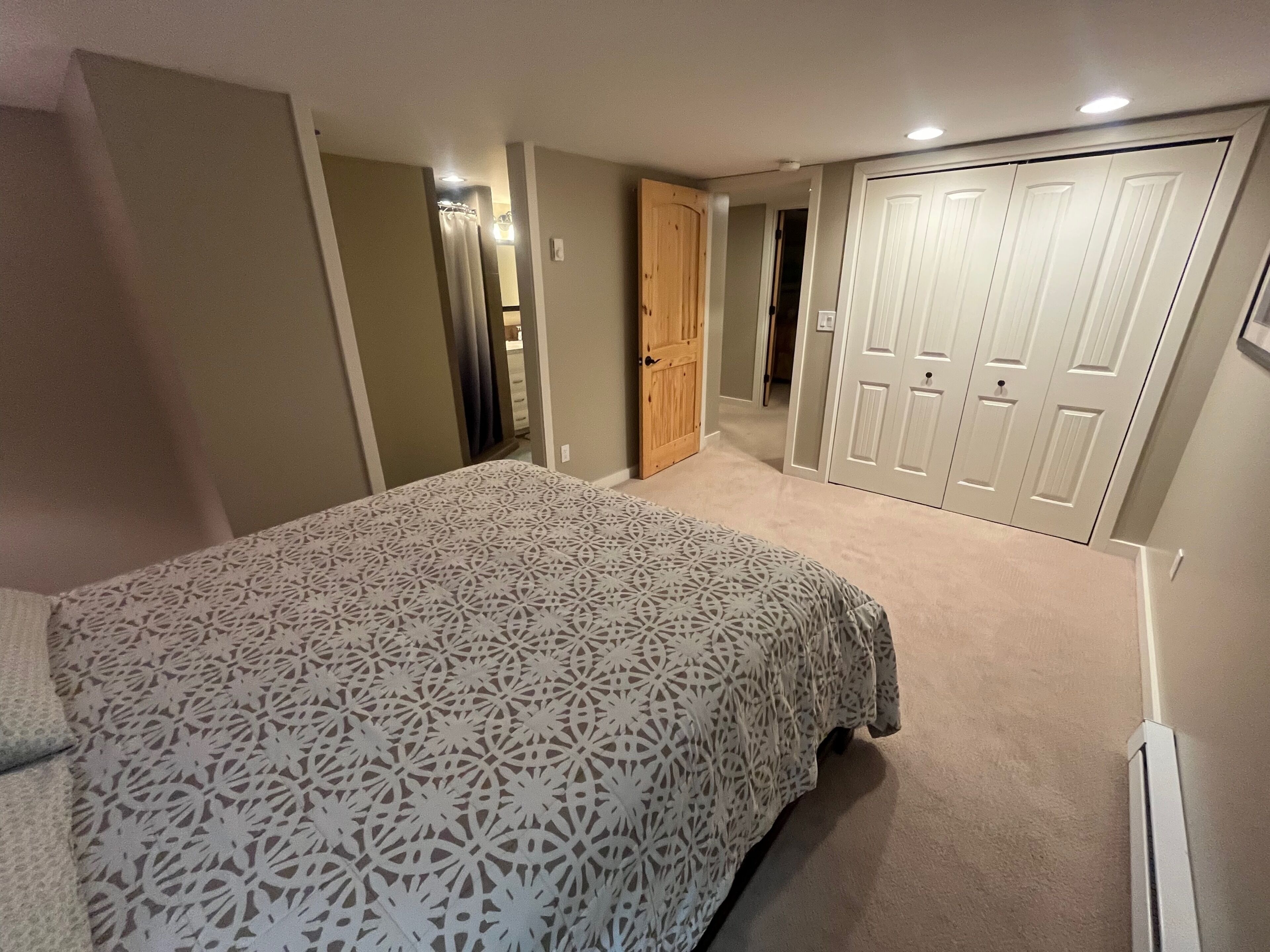 Une chambre à coucher comprenant un lit, une armoire et une porte donnant sur une autre pièce.