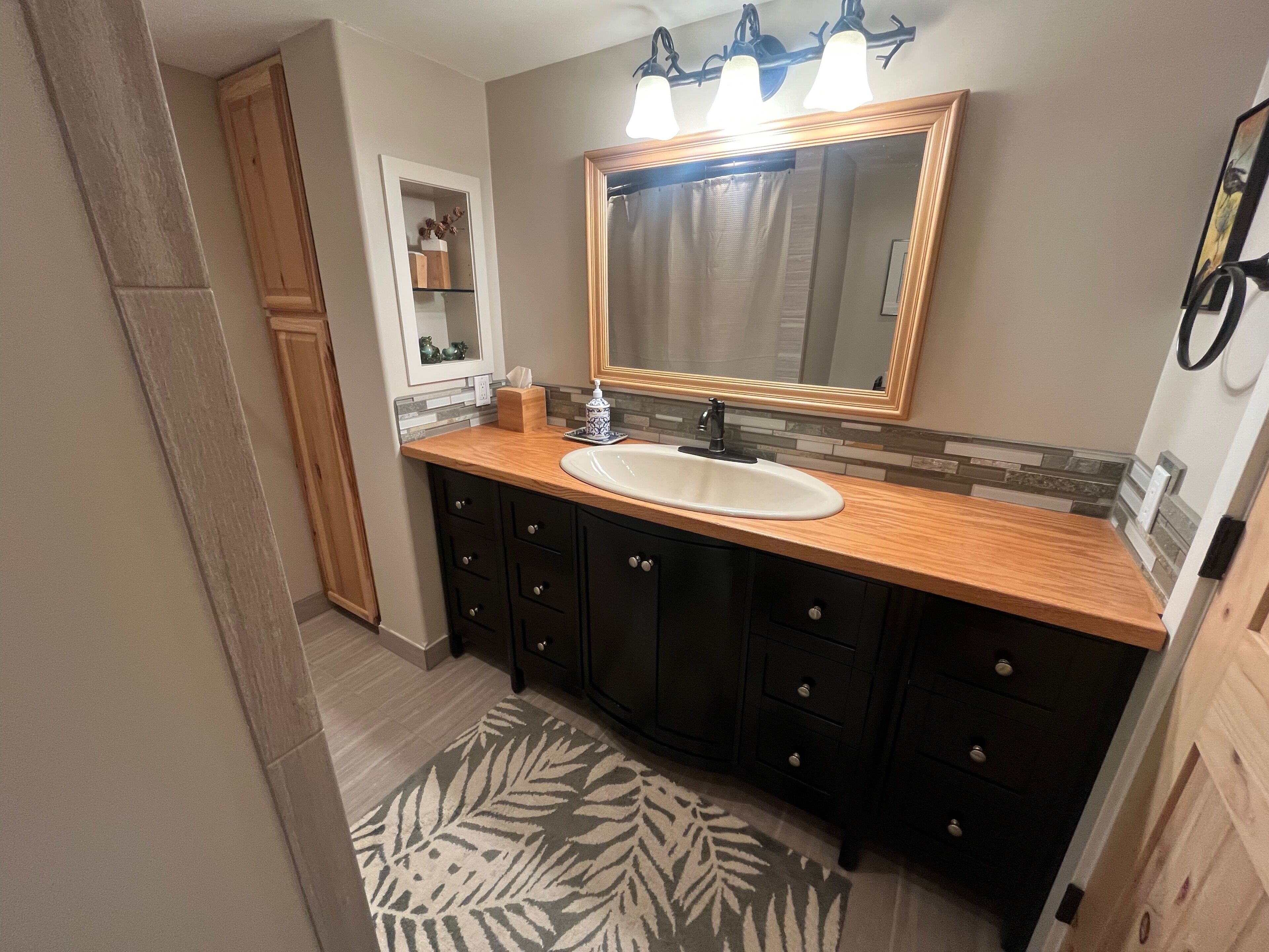 Une salle de bain avec un meuble-lavabo en bois, un grand miroir et un évier.