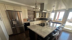 A modern kitchen with stainless steel appliances, a central island, and a view to the outdoors. - Private 3-bedroom Guesthouse with beautiful views of Kachemak Bay. (Homer)