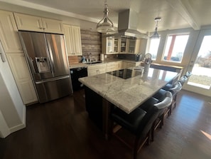 A modern kitchen with stainless steel appliances, a central island, and a view to the outdoors. - Private 3-bedroom Guesthouse with beautiful views of Kachemak Bay. (Homer)