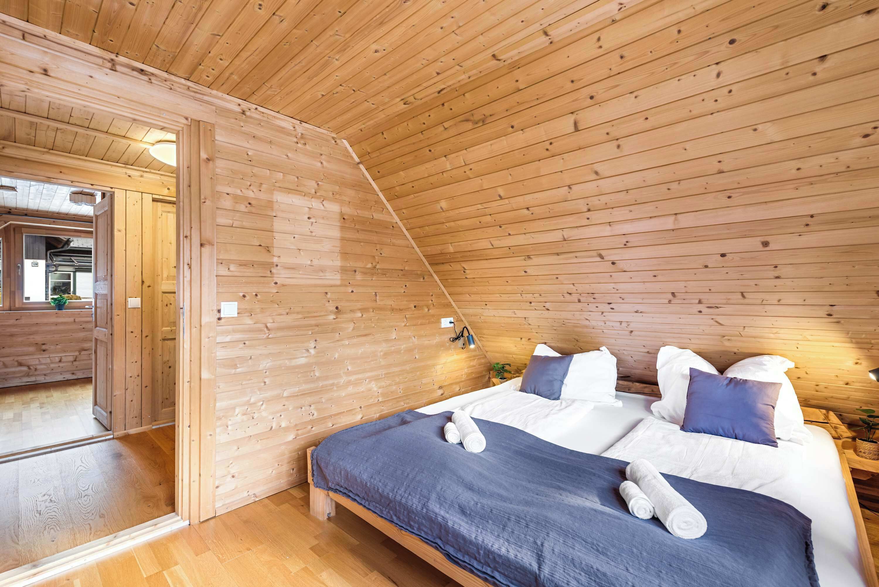 Une chambre aux murs lambrés, avec un lit, des oreillers et une table de chevet.