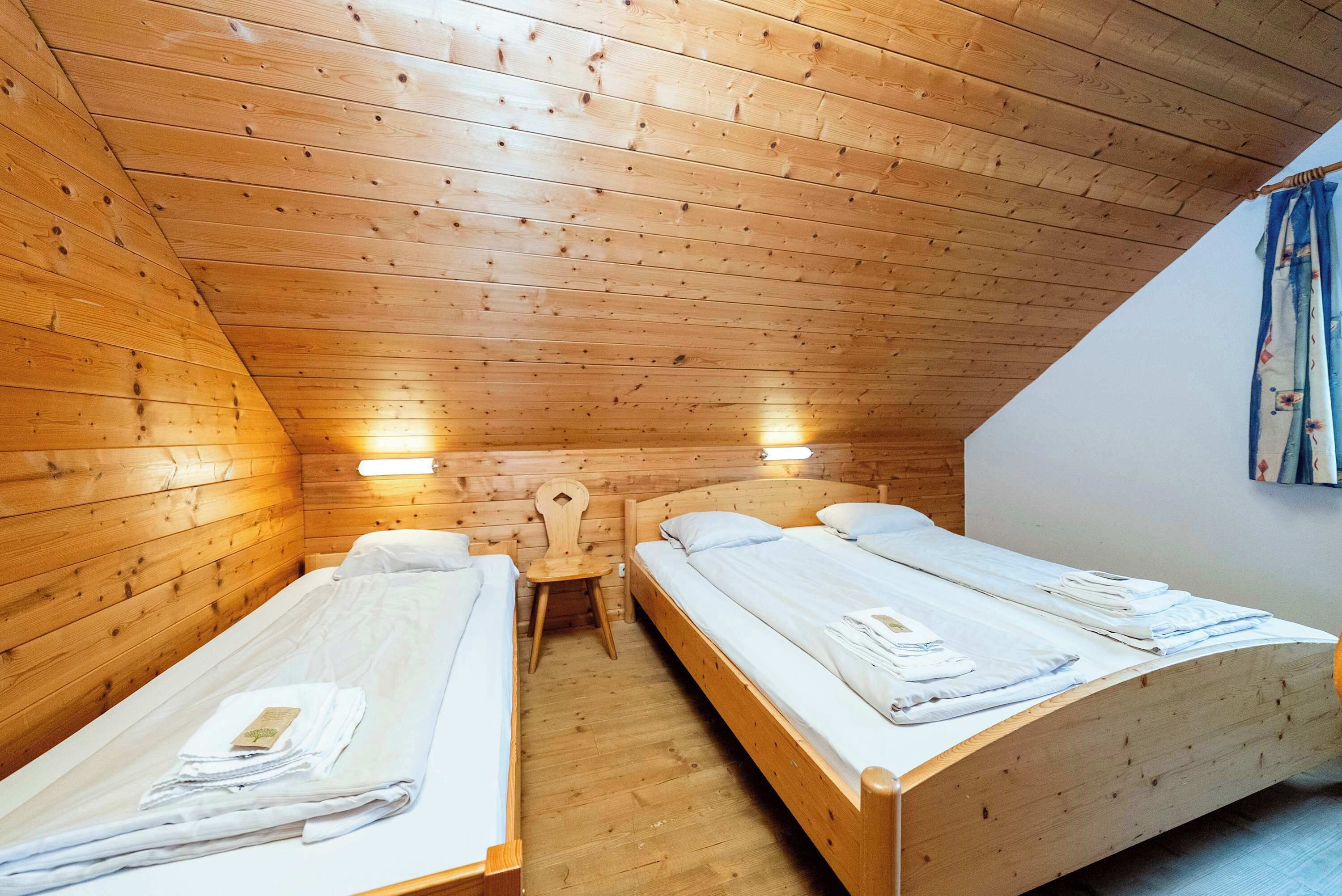 Een kamer met twee houten stapelbedden, een houten stoel en een kleine tafel.