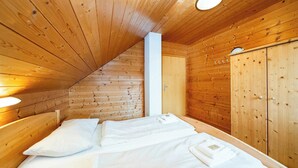 Une pièce de style cabane en bois, avec un lit, une armoire et un luminaire au plafond.