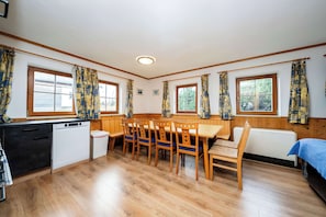 Een kamer met een houten eettafel, stoelen, een zwart aanrecht, een witte vaatwasser en een radiator.