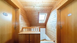 Un étroit couloir en bois, doté d’un plafond en pente, d’un petit banc et d’une lucarne.