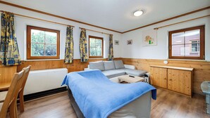 Une pièce confortable avec un lit, un canapé, une armoire en bois et une fenêtre avec des rideaux.