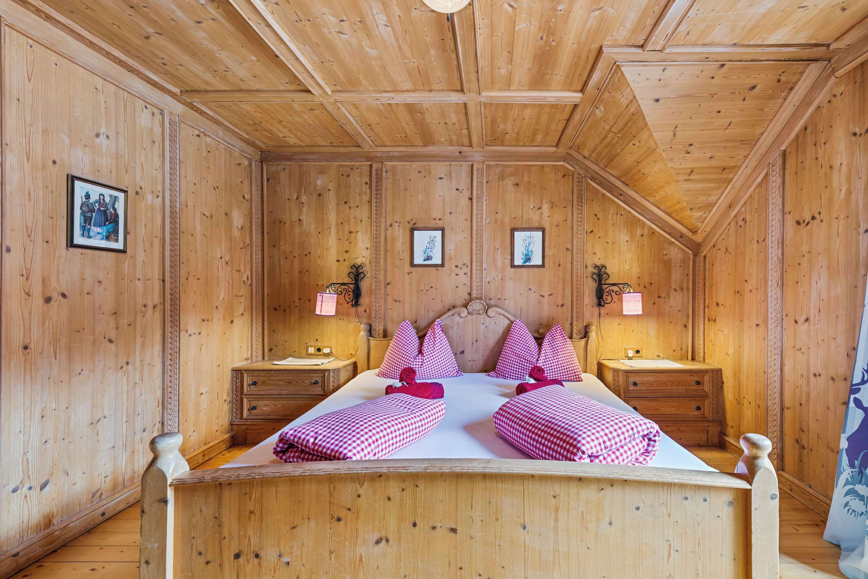 A wooden-paneled room with a bed, two nightstands, and wall-mounted lamps.